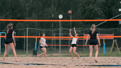 Mujer-Joven-Jugando-Voleibol-En-La-Playa-En-Un-Equipo-Que-Lleva-A-Cabo-Un-Ataque-Golpeando-La-Pelota.-Chica-En-Cámara-Lenta-Golpea-La-Pelota-Y-Realiza-Un-Ataque-A-Través-De-La-Red.